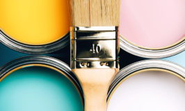 four paint cans and a dry paint brush